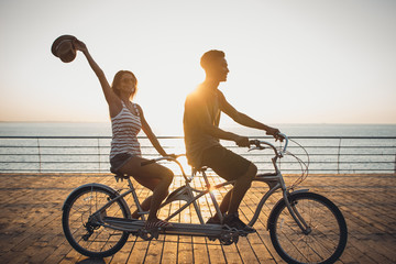 Portrait of a mixed race couple riding on tandem bicycle outdoors near the sea