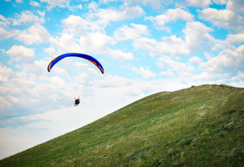 Trike with a parachute against the blue sky. Paragliding flying over the clouds