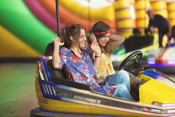 Two girls are having fun driving a dodgem car at the amusement park