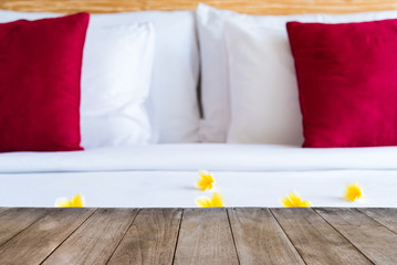 Perspective empty wooden table in front of hotel bed with flowers