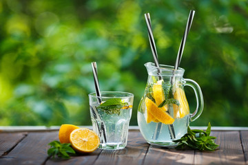Lemonade pitcher with lemons and mint on garden table