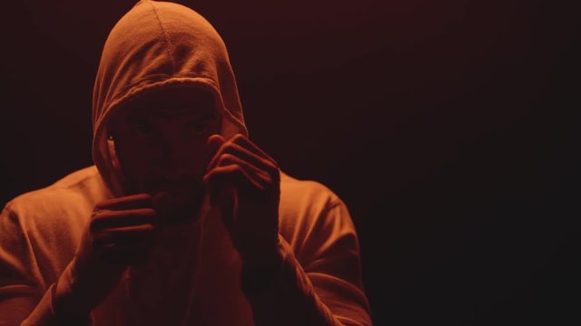 Close up shot of a muscular black man shadow boxing on a foggy dark red background, wearing a hoodie 