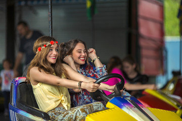 Obraz na płótnie Canvas Two cheerful young women are having fun in a bumper car at the funfair