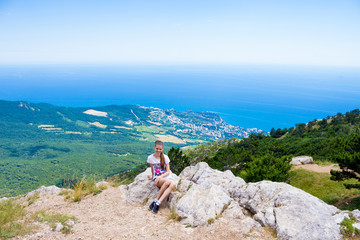 Young traveler on a mountain peak with sea and blue sky on Background