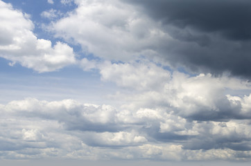 Fototapeta na wymiar Dark dramatic blue sky background with partial fluffy clouds Photo