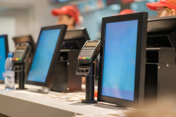Row of order desks with computer screen and card payment terinal in fast food restaurant - obrazy, fototapety, plakaty