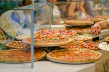 Variety of yummy pizzas under shopping window in pizzeria