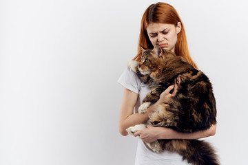 Beautiful young woman on a light background holds a cat, an allergy