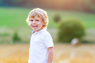 Naklejka na ściany i meble Happy blond kid boy enjoying sunset in wheat field.