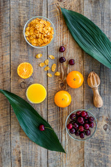 Preparing healthy summer breakfast. Muesli, oranges, cherry, on wooden table background top view