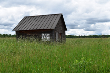 Obraz premium Abandoned cabin in a grassy field