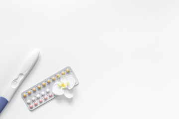 Pregnancy planning. Pregnancy test and contraceptive pills on white background top view copyspace