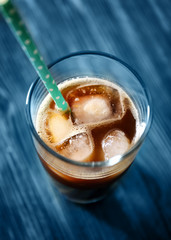 Glass of cold brew coffee and straw on wooden table