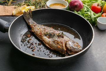 Frying pan with tasty trout fish on table