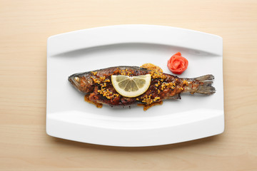 Plate with tasty fried fish on light background