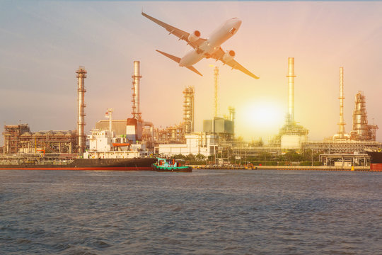 View of airplane flying, oil refinery industry plant and river at sunset as transportation, energy and industrial concept