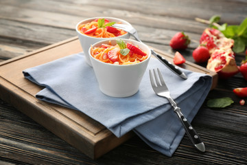 Yummy carrot strawberry salad in cute white bowls on wooden table
