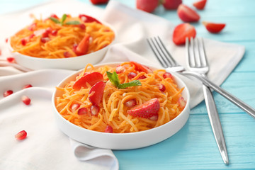 Cute plates with delicious carrot strawberry salad on blue wooden table