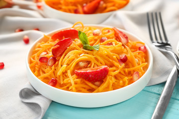 White round plate with delicious carrot strawberry salad on table, closeup