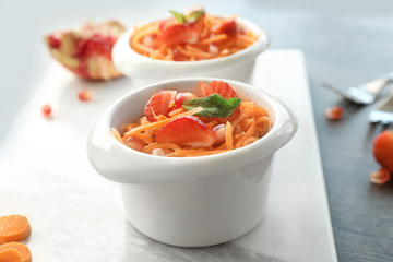 Cute white bowl with yummy carrot strawberry salad on marble board