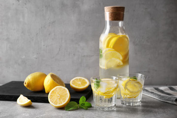 Bottle and glasses of fresh lemonade on table