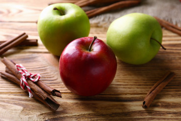 Apples with cinnamon sticks on wooden background