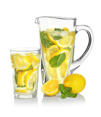 Jug and glass with tasty refreshing lemonade on white background