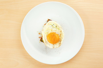 Plate with delicious sunny side up egg and bread slice on wooden background