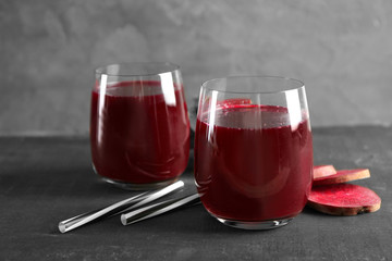 Fresh healthy smoothie in glasses with straws and slices of beets on table