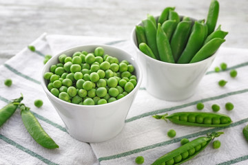 Bowls with fresh green peas on table