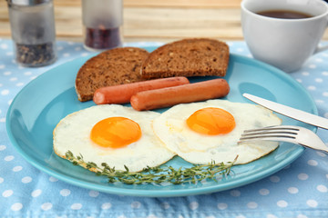 Homemade over easy fried eggs with sausages and bread on plate