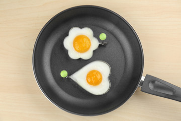 Frying pan with tasty over easy eggs in molds