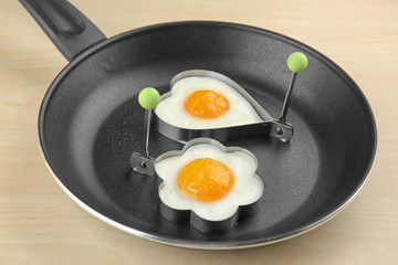 Frying pan with tasty over easy eggs in molds