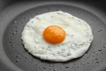 Tasty over easy fried egg in pan, closeup