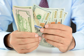 Businessman counting money,US dollar (USD) bills, on the table