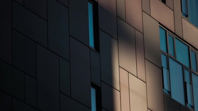 Modern building exterior with clouds and shadows reflecting in windows in time-lapse 