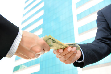 Hands of businessmen passing money, US dollar bills