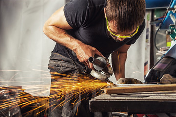 man grinding metal with a angle grinder - Powered by Adobe
