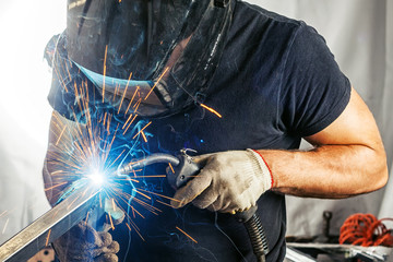 man weld  a metal  with a  welding machine - obrazy, fototapety, plakaty