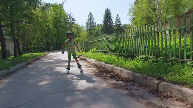 Young boy roller skating in countryside in summer day