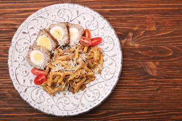 Boiled eggs in a layer of sausage meat wrapped with pasta