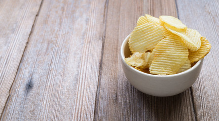 potato chips in a white bowl on wooden table