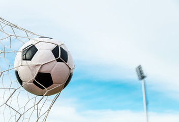 Soccer football in Goal net with the sky field.