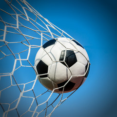 Naklejka premium Soccer football in Goal net with the sky field.