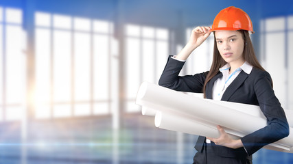 Young beautiful business woman and creative designer standing over blured interior background