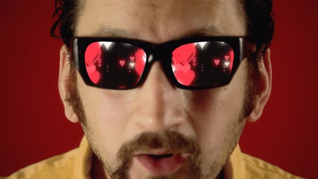 A funny ugly man with hypnotic glasses, looking at big red hearts falling down like in a popular sci-fi movie.
