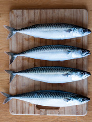 Four mackerel fish on kitchen board