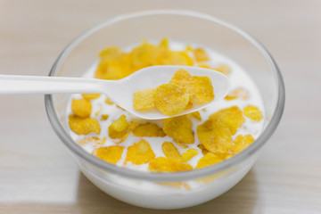 bowl of corn flakes and spoon on wood background