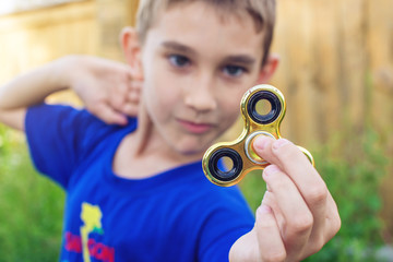 A boy plays with spinner twisting it in his hand on outdoors. Trends in children's anti-stress toys