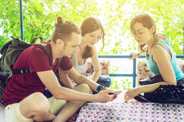 A group of young people relax outdoors and watch videos from your phone. Friends smile and laugh together